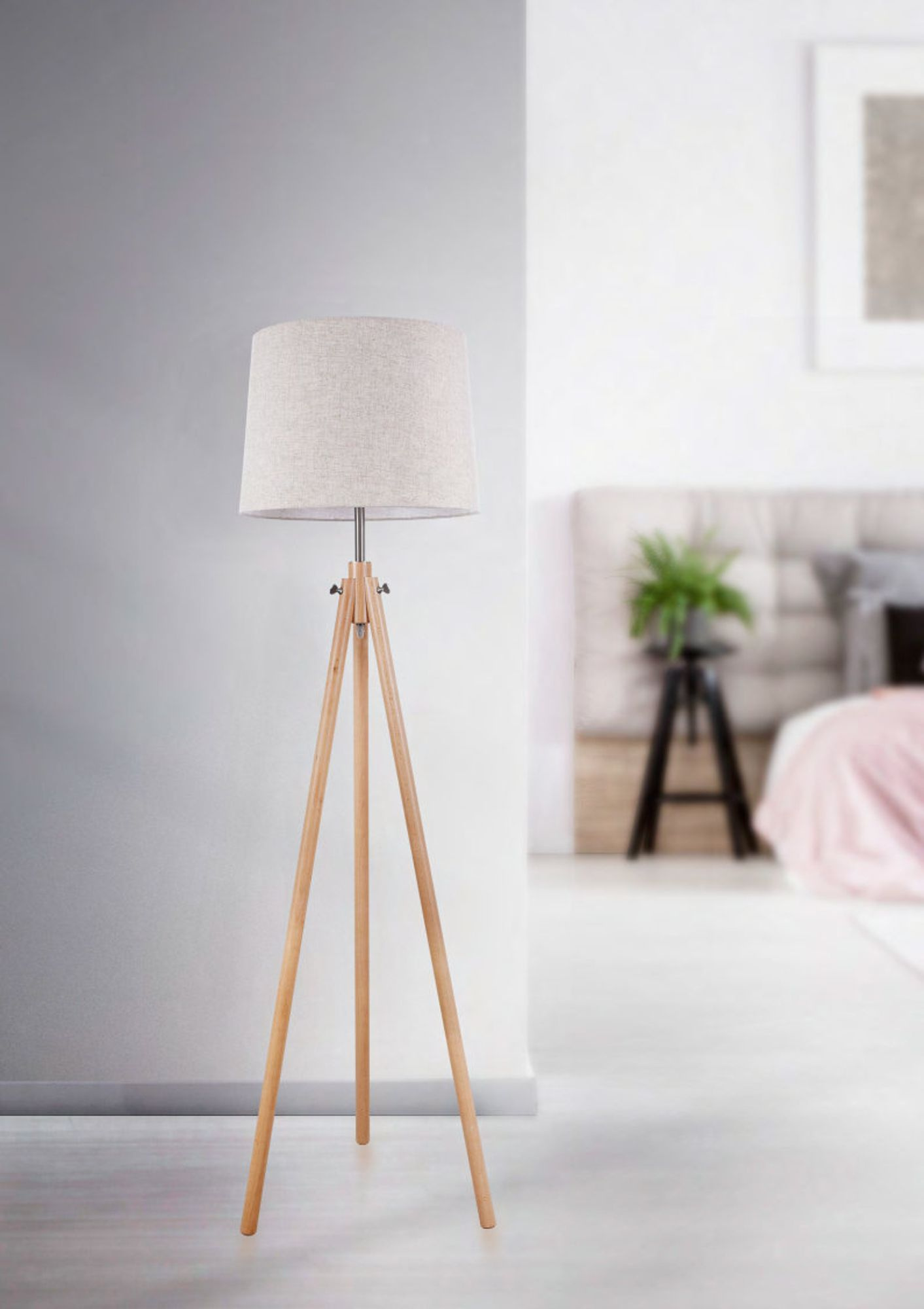 lampa podłogowa na drewnianym trójnogu świecąca ciepłym światłem